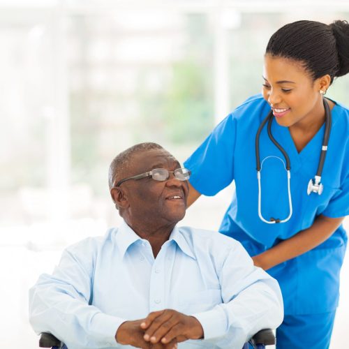 beautiful african nurse taking care of senior patient in wheelchair